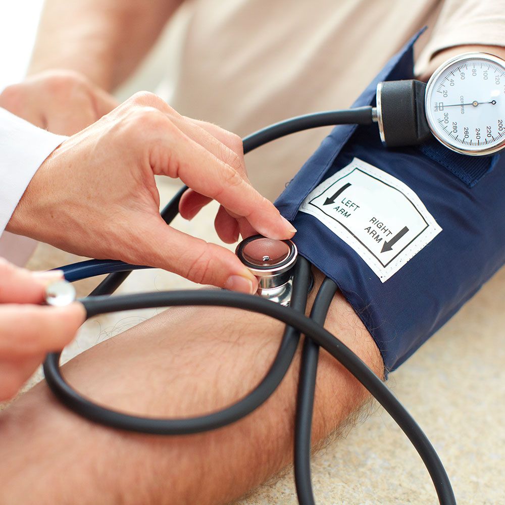 Blutdruckmessung an einem Arm mit Manschette und Stethoskop